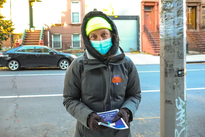 A member of the NYC Election Observer Corps. hands out voting information outside a poll site.